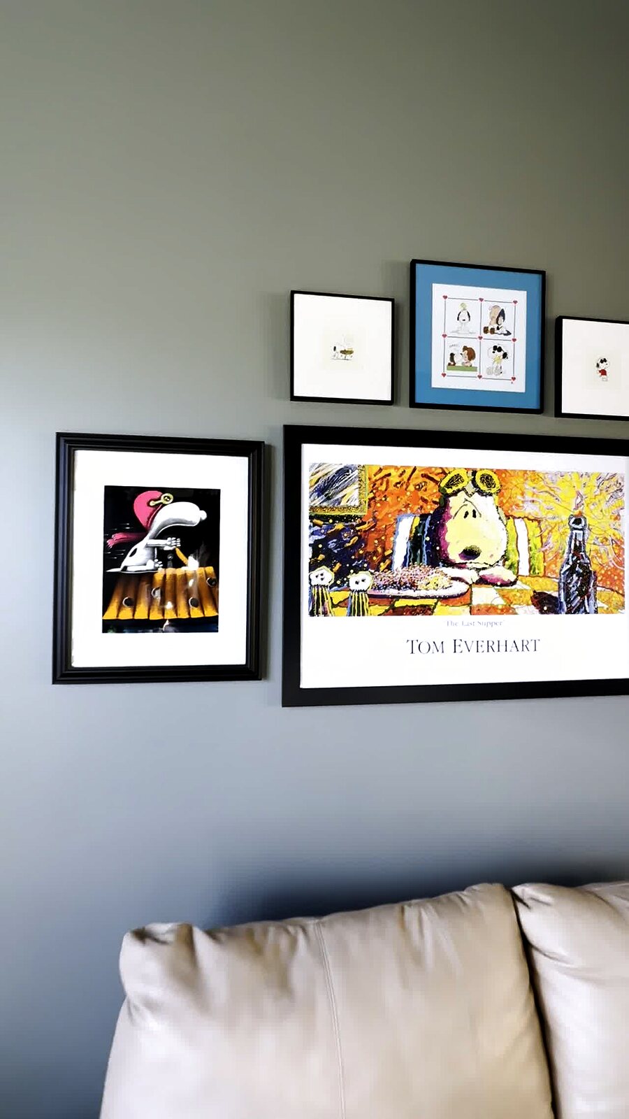 Gallery wall above the sofa centered on the Tom Everhart Snoopy Last Supper print